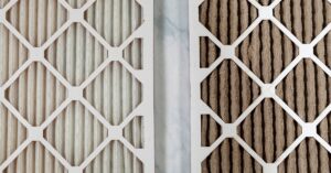 Two HVAC air filters.; one is a dark gray color due to a buildup of air containments while the other is white.