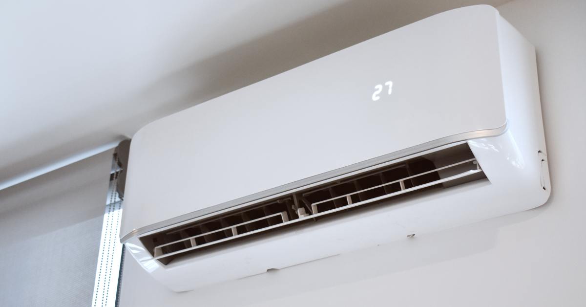 A white mini-split unit mounted on a light-colored wall near the ceiling displays "27" on its digital screen.